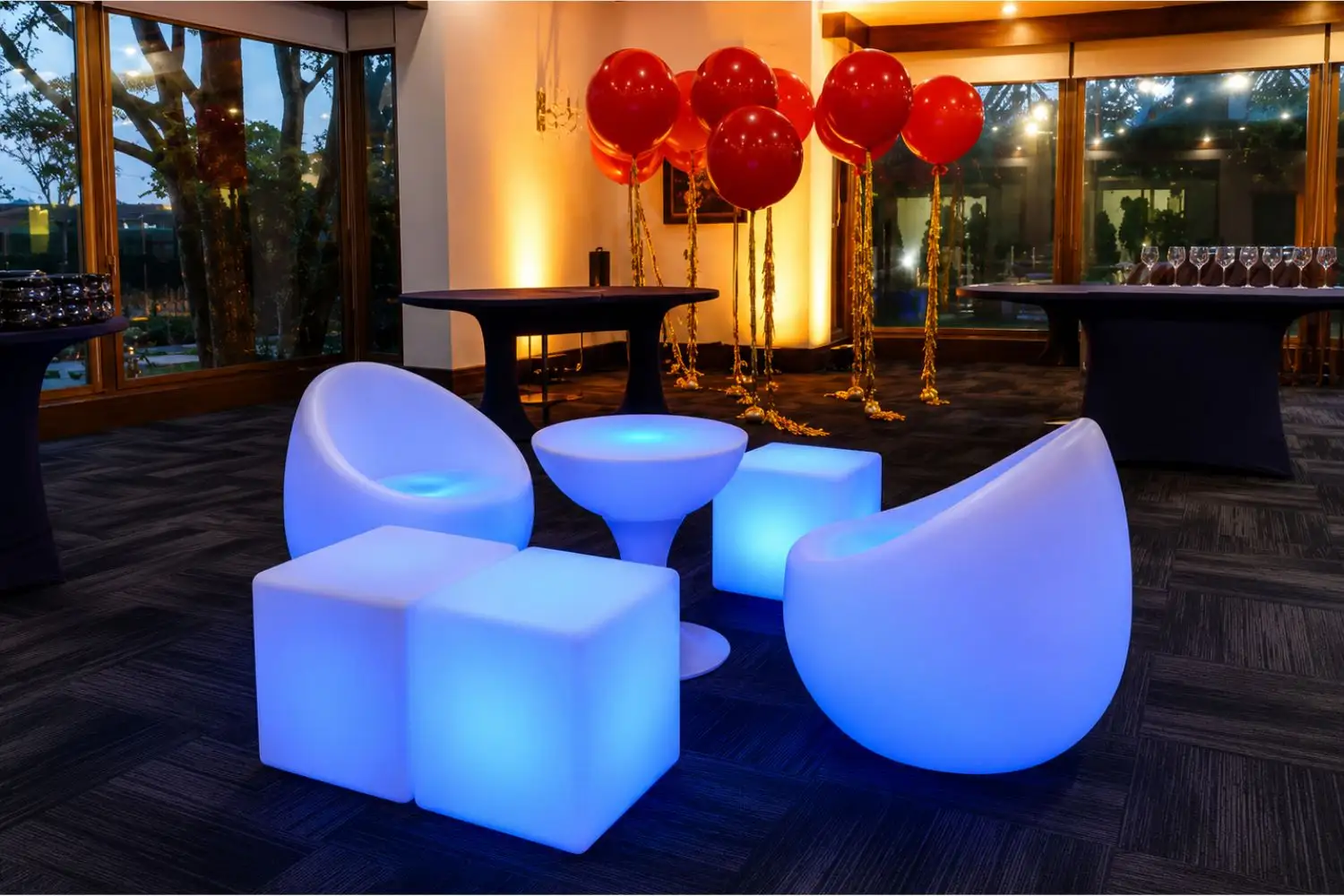 Poltronas, cubos y mesa LED iluminados en azul en salón de eventos